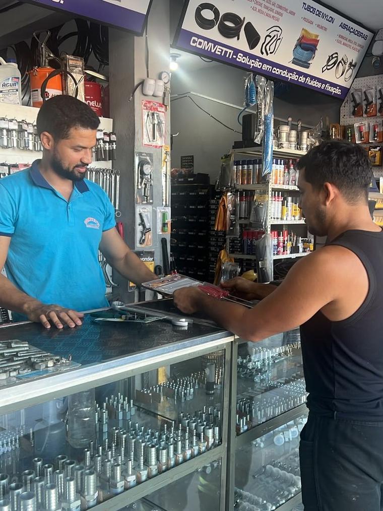 Atendente da Comvetti no balcão, com o cliente escolhendo ferramenta sobre a vitrine de terminais