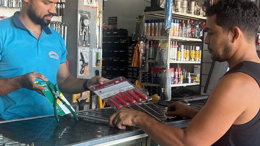 Atendente da Comvetti mostrando ferramenta ao cliente sobre o balcão