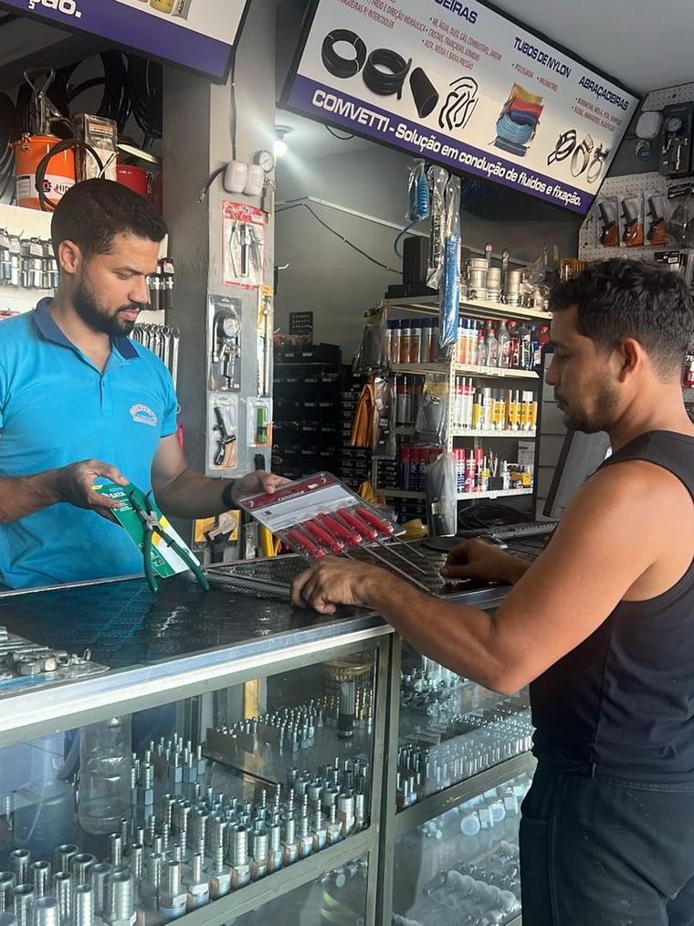 Atendente da Comvetti mostrando ferramenta ao cliente sobre o balcão